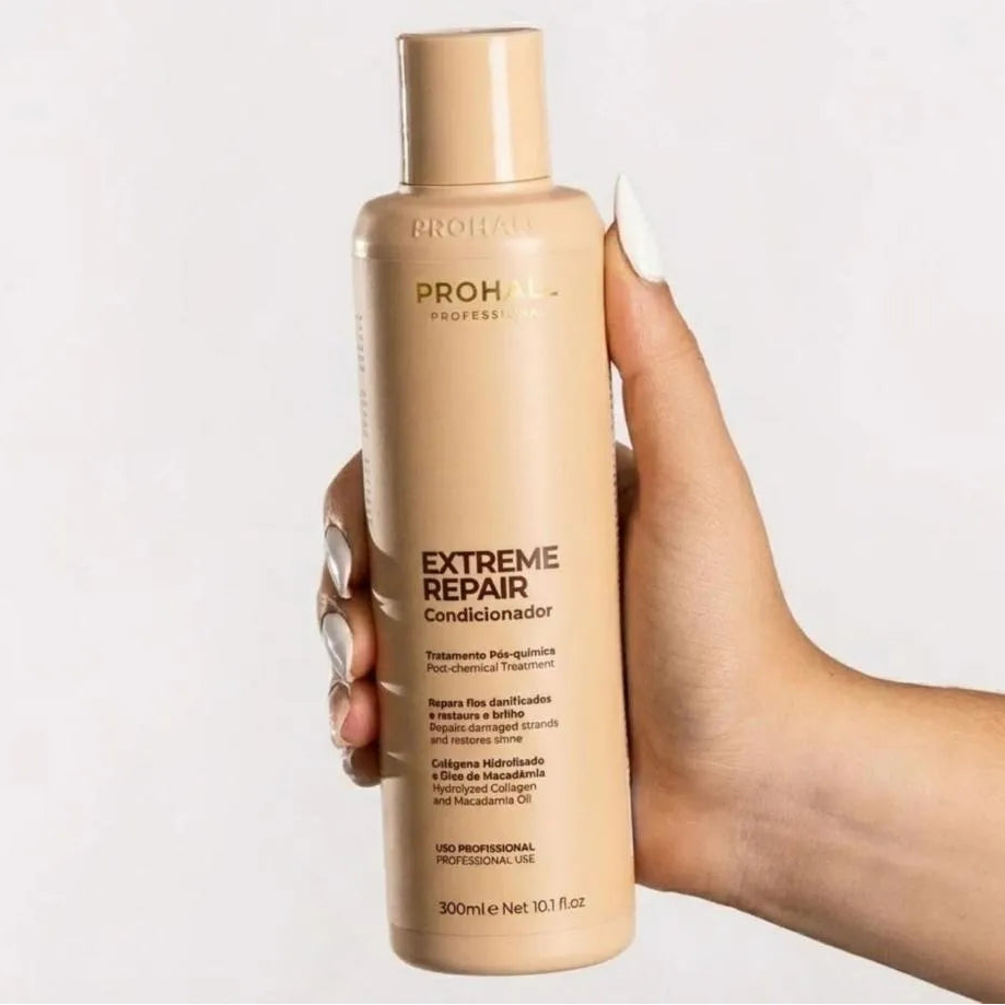 Hand holding a bottle of ProHall Extreme Repair conditioner with a plain background