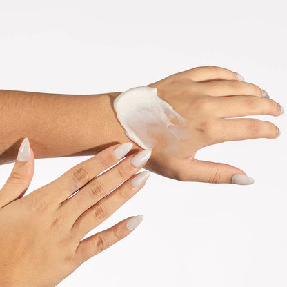 Hand applying cream to another hand on a white background