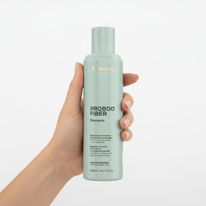 Hand holding a bottle of ProBoo Fiber shampoo against a white background