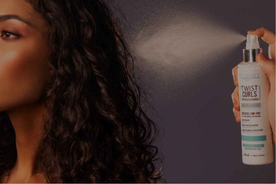 Person with curly hair holding a bottle of 'Twist Curls' product against a dark background