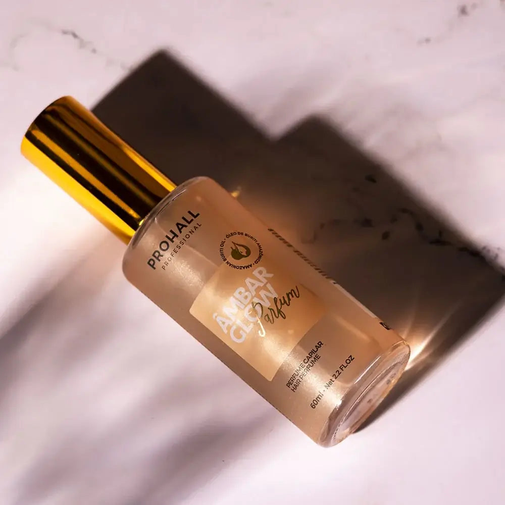 Hair perfume bottle with gold cap on a marble surface