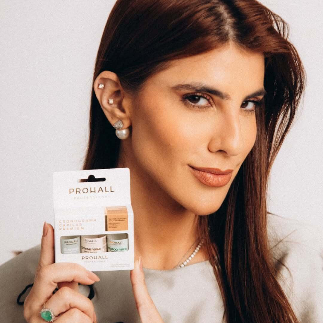 Woman holding a Prohall product package against a plain background