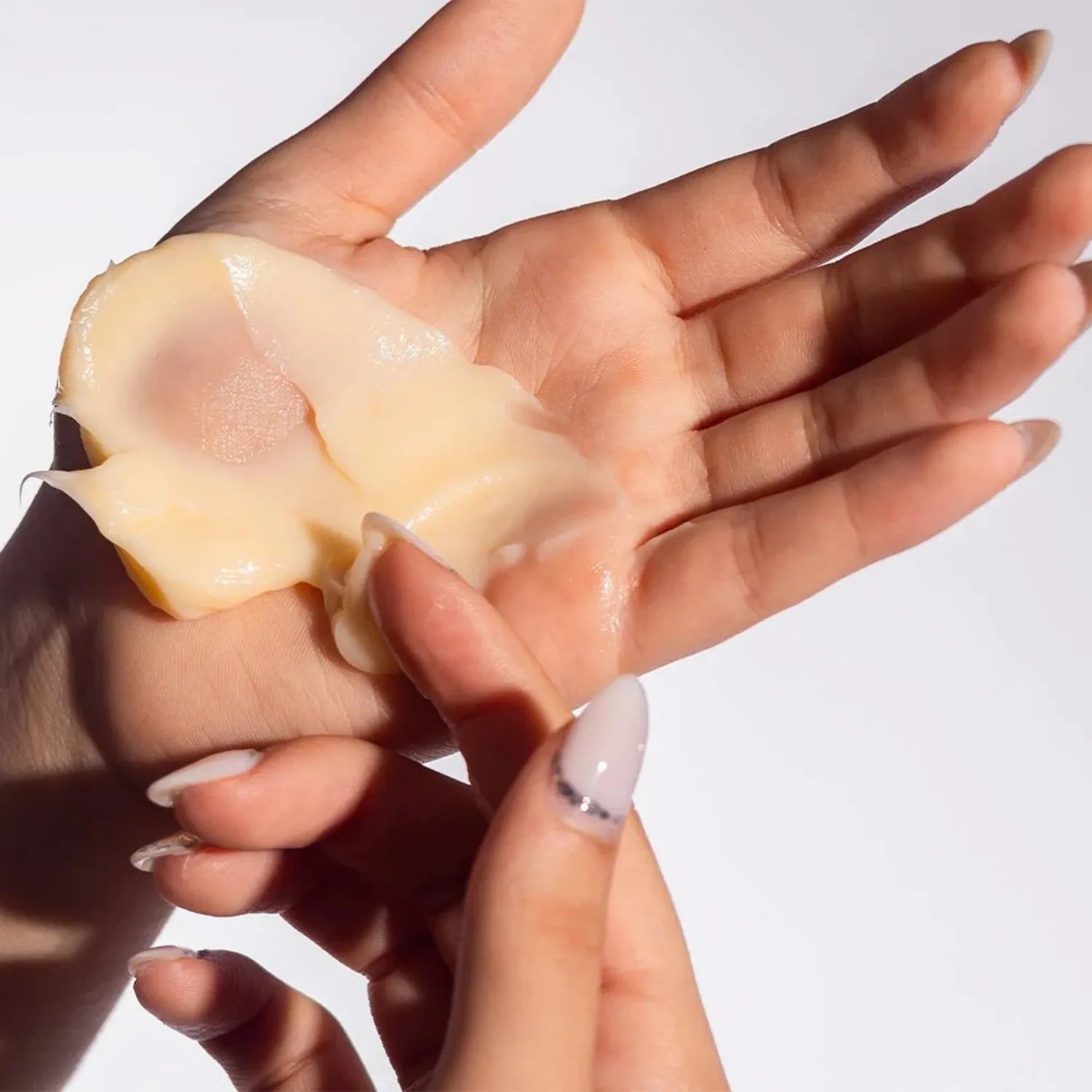 Hand holding and spreading Extreme Repair Mask in the hands with a white background