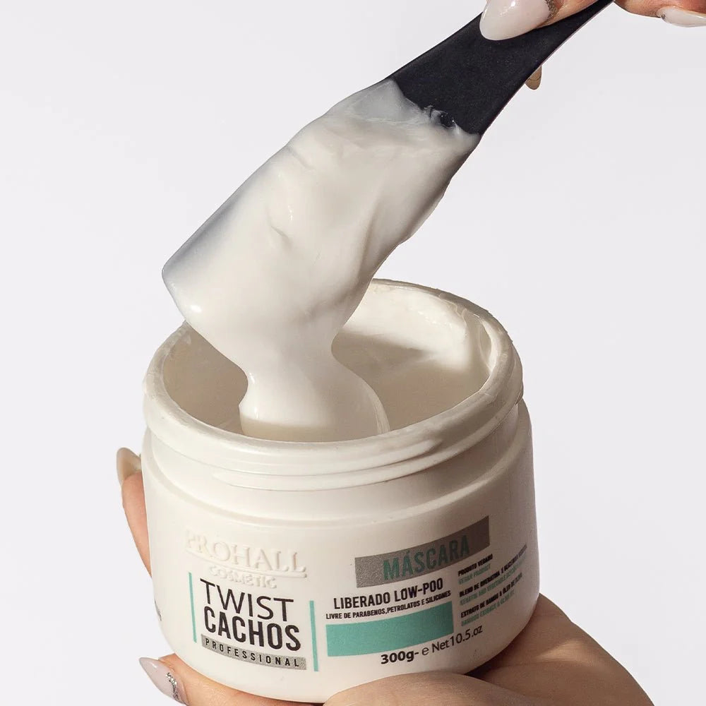 Jar of hair mask with a spatula scooping out white cream against a light background