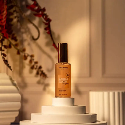 Amber glow serum bottle on a white pedestal with decorative elements in the background