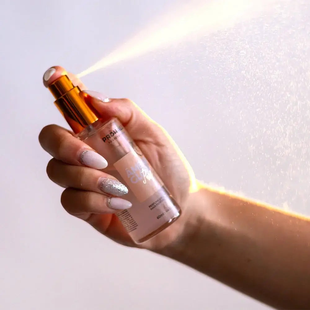 Hand holding a hair perfume bottle with a white background