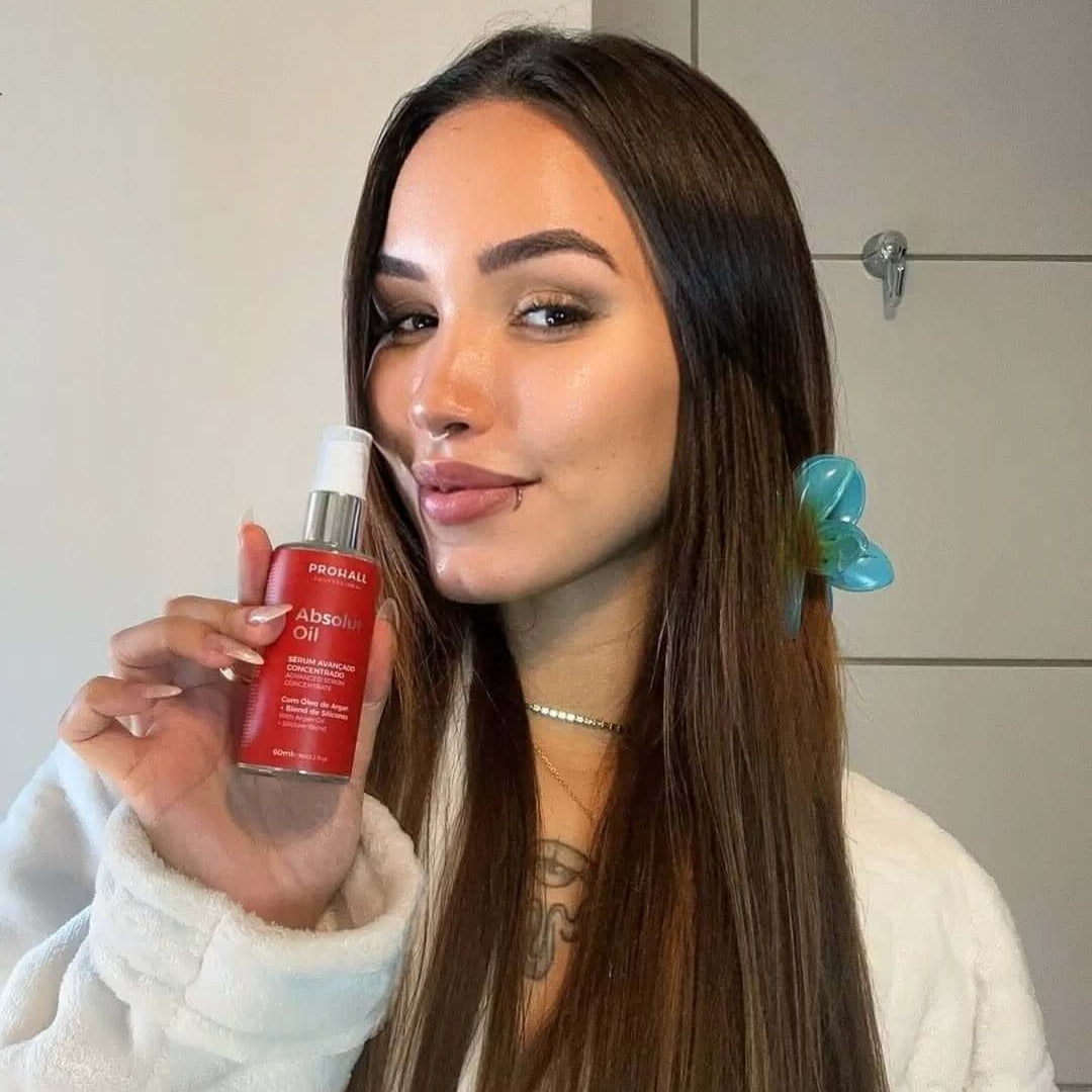 Woman holding a red skincare bottle in a bathroom setting