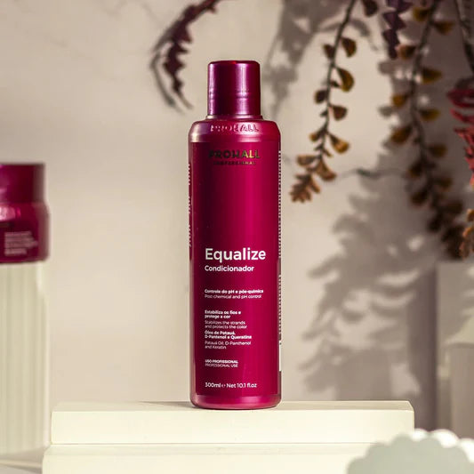 Red bottle of 'Equalize' conditioner on a white surface with a blurred background